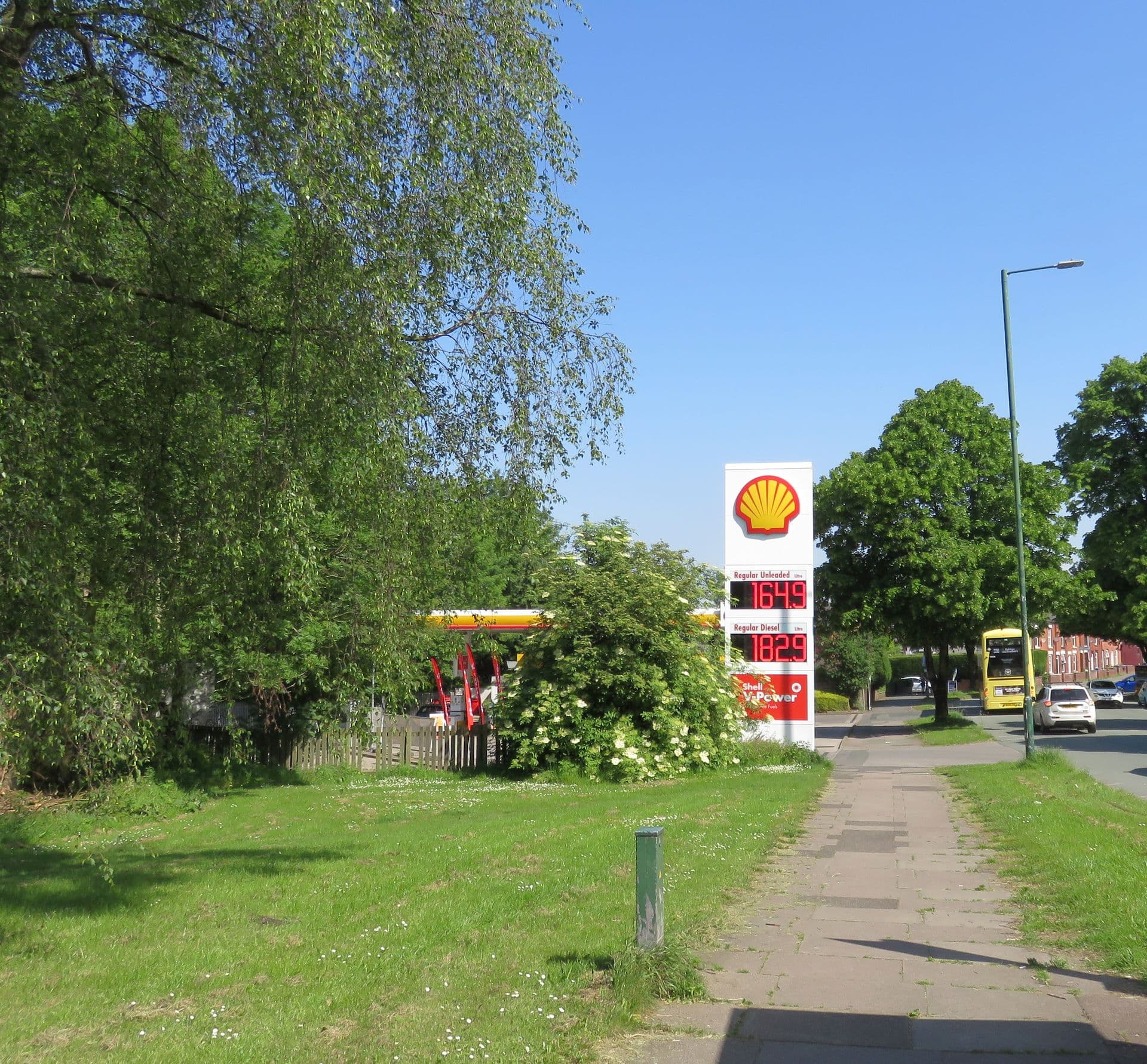 A Shell fuel price sign in England displaying 'Regular Unleaded 164.9' and 'Regular Diesel 182.9' pence per litre, photographed May 2026.